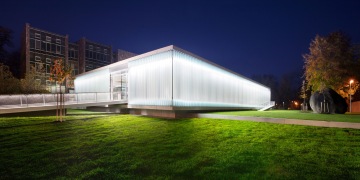 The modern, glass-walled Lidická branch building of the South Bohemian Research Library, illuminated at dusk.